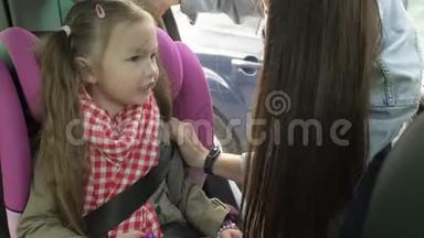 一家人去度假时，美丽的、有爱心的母亲把安全带系在汽车后座上